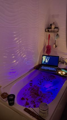 a bathtub filled with water next to a laptop computer