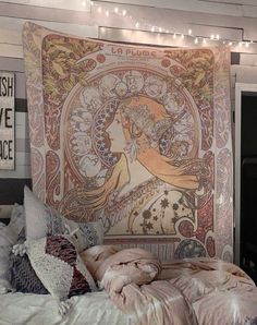 a large tapestry hanging on the wall above a bed with pillows and blankets in front of it