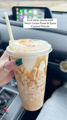 a woman is holding a cup of coffee in her hand while she sits in the car