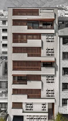 the building has many windows and balconies on it's sides, along with other buildings in the background