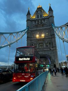 a red double decker bus driving across a bridge