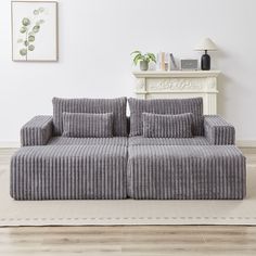 a gray couch sitting on top of a wooden floor next to a white fireplace and wall