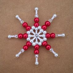 a red and white beaded snowflake ornament on a brown surface