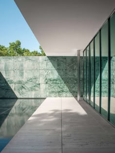 the inside of a building with glass walls and water reflecting it's reflection in the pool