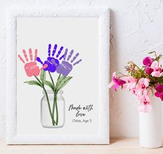 a vase filled with pink and purple flowers on top of a wooden table next to a plant