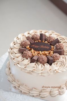 a white cake with chocolates and nuts on top