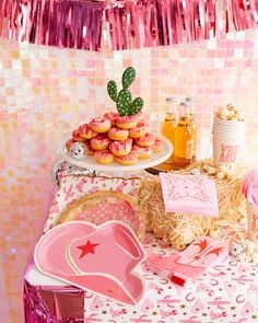 a table topped with pink and gold desserts next to confetti covered donuts