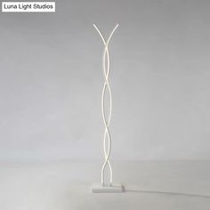 a white sculpture is standing in the middle of an empty room with light shining on it