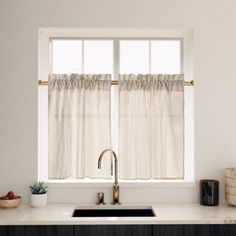 a kitchen sink sitting under a window next to a counter