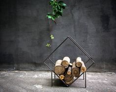 a stack of logs sitting on top of a metal stand next to a tree branch