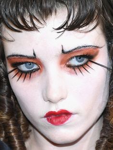 a close up of a person with makeup and eyeliners on their face, looking at the camera