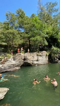 people are swimming in the water near some rocks