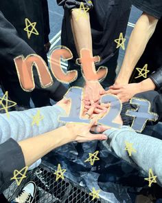 several people are holding hands in the middle of a circle with stars around them that spell out numbers