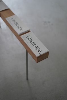 two wooden signs with words on them sitting on top of a metal pole in the middle of a floor