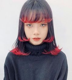 a woman with red and black hair wearing a turtle neck sweater