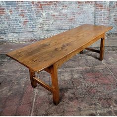 a wooden bench sitting on top of a cement floor next to a brick wall in an old building