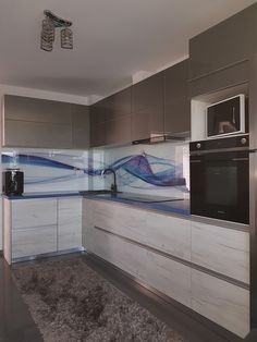 a modern kitchen with stainless steel appliances and marble counter tops, along with an area rug on the floor