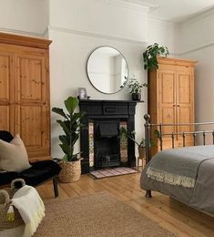 a bedroom with a bed, dresser and mirror in it's corner area next to a fireplace