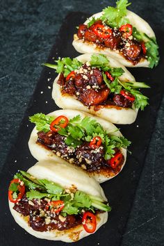 four tacos with meat and vegetables on a black plate