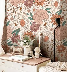 a room with flowers on the wall and a white dresser