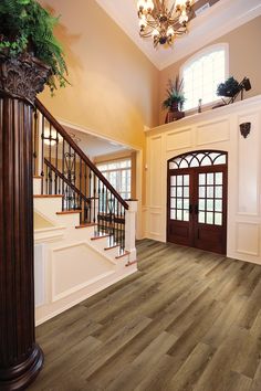 a large foyer with wood floors and chandelier above the stairs, leading to an entryway