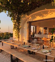 an outdoor dining area with wooden benches and tables set up for dinner on the patio