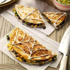 three quesadillas with black beans and cheese on paper next to a knife