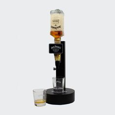 an old fashioned beverage dispenser with two glasses next to it