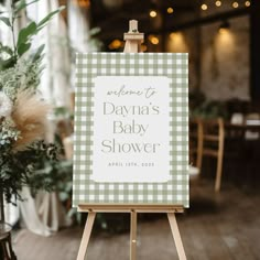 a green and white checkered sign sitting on top of a easel next to a potted plant