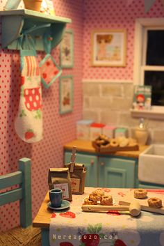 a dollhouse kitchen with blue cabinets and pink wallpaper on the walls, including a table