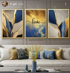 three paintings on the wall above a couch in a living room with white furniture and gold accents