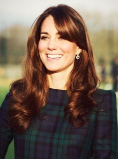 a woman with long brown hair wearing a green and black dress smiling at the camera