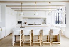 a kitchen with white counter tops and stools next to an island in the middle