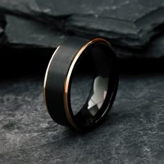 a black and gold wedding ring on top of a stone slabd surface with the center in