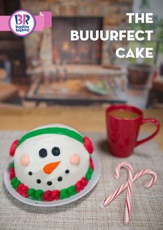 a decorated cake sitting on top of a white plate next to a red cup and candy cane