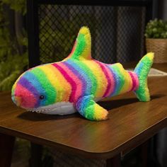 a colorful stuffed fish sitting on top of a wooden table