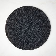 a round black woven object on a white surface