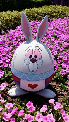 an inflatable bunny sitting on the ground surrounded by pink flowers