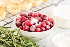 a bowl filled with cranberries and powdered sugar next to other pastries