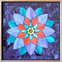 a colorful flower made out of stained glass in a wooden frame on a purple background