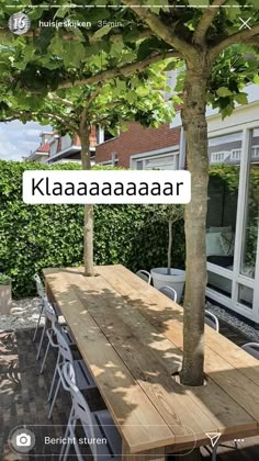 a wooden table with chairs under a tree