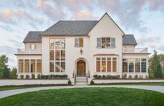 a large white house sitting on top of a lush green field