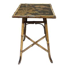 a small wooden table with a black and gold design on it's top, against a white background