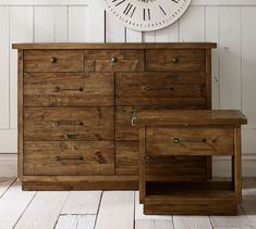 a large clock on the wall next to a dresser with drawers in front of it