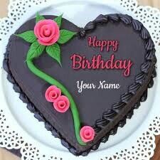 a heart shaped chocolate cake with pink roses on it and the words happy birthday yogesh