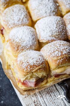 powdered sugar covered pastries sitting on top of a cutting board