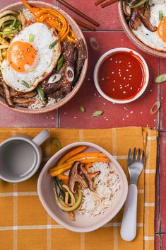 two bowls filled with food on top of a red and yellow table cloth next to silverware