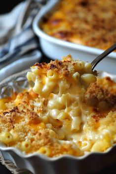 a spoon full of macaroni and cheese being lifted from a casserole dish