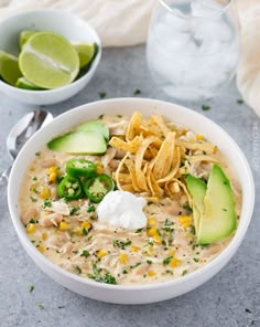 a bowl of chicken tortilla soup with avocado and sour cream on the side