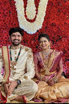 two people sitting next to each other in front of flowers